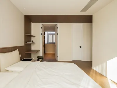 A minimalist bedroom with neutral-toned textiles and a modern design.