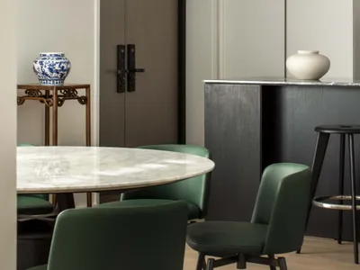 Contemporary kitchen with marble countertops and green leather chairs, featuring a minimalist design with white pendant light