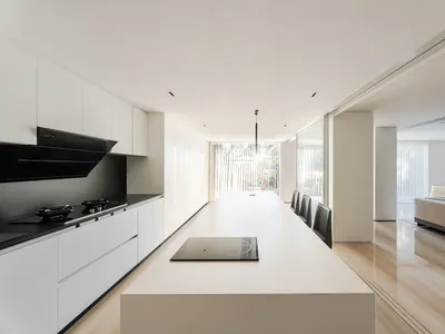 A modern, minimalist residential kitchen featuring white marble countertops and a sleek, clean design.