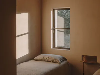 A minimalist bedroom with neutral-colored walls and a single window.
