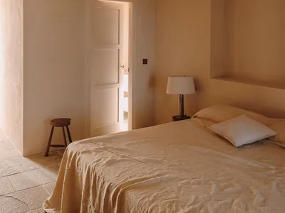 A minimalist bedroom with beige plaster walls and a simple bed setup.