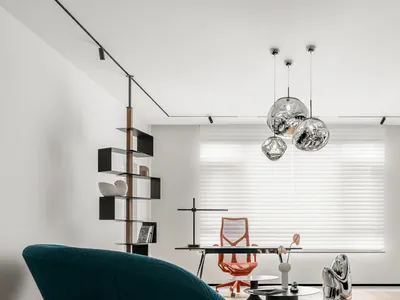 A minimalist home office featuring a sleek, metallic desk and orange chair, surrounded by contemporary decor and a large wind