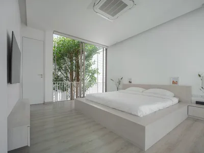 一間簡約臥室設有懸浮式床、大型窗戶，以及通往陽台的門。