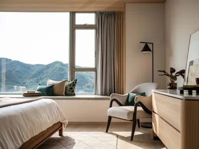 A modern minimalist bedroom featuring wooden furniture, fabric upholstery, and metallic accents.