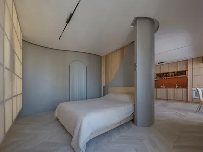一間現代臥室，搭配淺色木地板與白色床罩的床鋪。