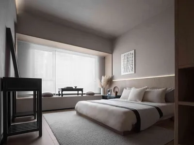A minimalist bedroom with neutral tones, featuring a bed, nightstand, and artwork above the bed.