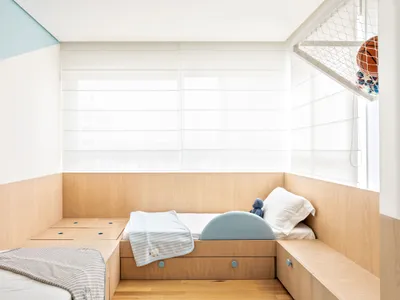 Minimalist bedroom featuring wood furniture and a bed with a blue blanket and pillow.