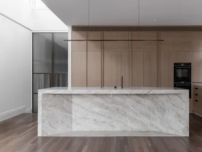 A modern kitchen featuring marble countertops and wooden cabinets.
