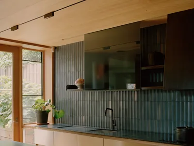 A modern kitchen featuring metallic tiles backsplash and wood cabinets.