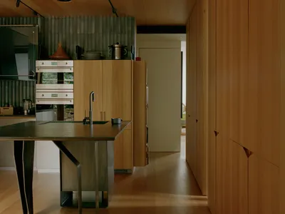 A modern kitchen featuring wooden cabinets and a stainless steel island with a sink and faucet.