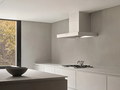 Minimalist kitchen with concrete and white surfaces, featuring a large window