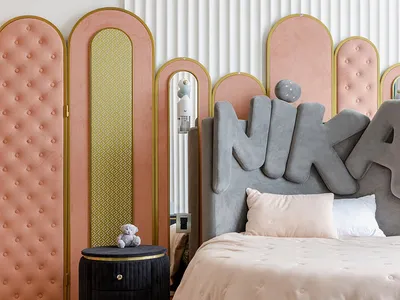 A bedroom with minimalist design, featuring a fabric headboard, wood flooring, and a carpet with abstract patterns.