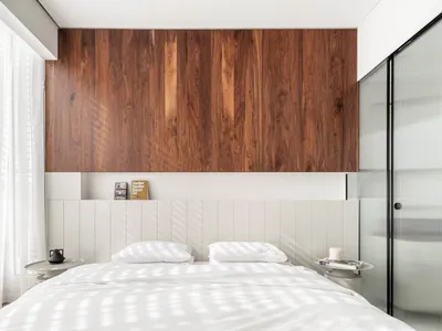 A modern minimalist bedroom featuring a wooden wall and white paneling.