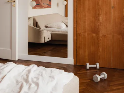 Modern minimalist bedroom with wooden wardrobe, fabric bed, and decorative mirror