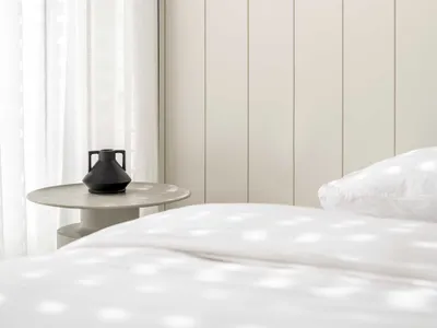 Minimalist bedroom featuring a wooden headboard, white curtains, and a white bed.