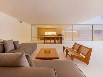 Modern minimalist living room featuring wood furniture, fabric seating, and glass walls.