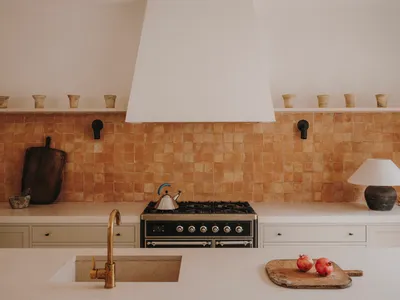 A modern minimalist kitchen with a ceramic tile backsplash, wooden cabinets, concrete countertops, and a stainless steel stov