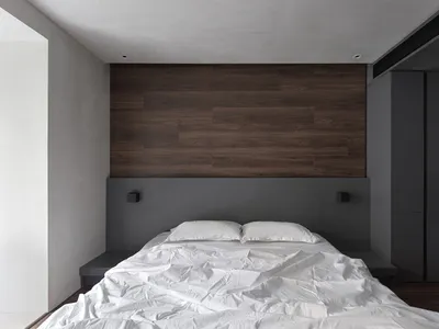 Minimalist bedroom featuring a white bed with wood accents.
