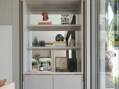A modern bar with built-in shelves and a marble countertop, featuring various decorative and functional items.