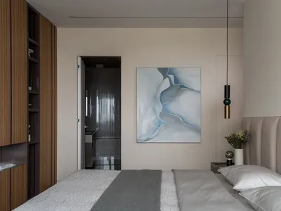 Modern bedroom featuring a neutral-toned color palette and soft textiles, with an abstract painting on the wall.