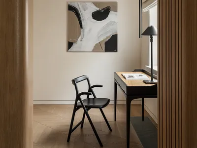 A modern home office featuring a black chair and desk with wooden furnishings.