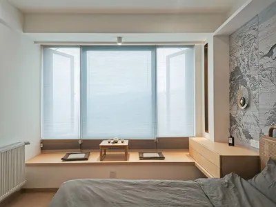 A minimalist bedroom featuring concrete, fabric, and wooden elements.