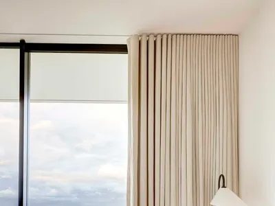 Modern minimalist bedroom featuring linen blinds and a serene view of a vineyard.