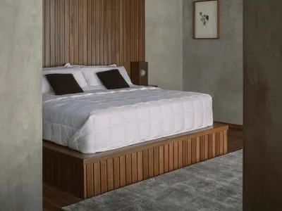 A minimalist bedroom with a wooden platform bed and a tall wooden panel wall.