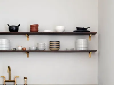 A minimalist modern kitchen featuring dark wooden cabinets and brass fittings.
