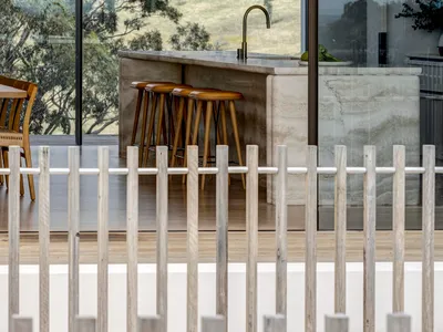 A modern minimalist kitchen with a concrete countertop and a view of lush green hills through large windows.
