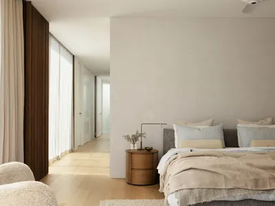 A modern minimalist bedroom with neutral-toned fabrics and furniture.