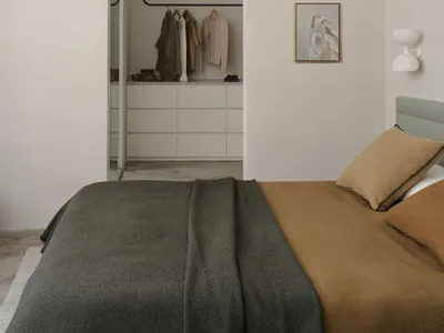 Minimalist bedroom with a neutral blanket and a closet in the background.