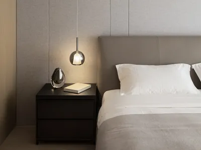A minimalist bedroom featuring a fabric-covered bed, a sleek nightstand, and modern lighting.