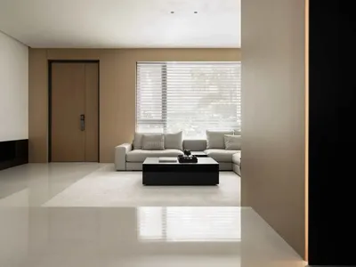 Modern minimalist living room with light wooden walls, white sofa, and black coffee table with a book and remote.
