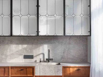Modern kitchen featuring wood cabinets, concrete countertops, and glass cabinets.