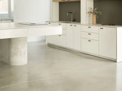 Modern minimalist kitchen featuring concrete countertops, wood cabinetry, and metal accents.