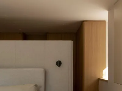 Modern minimalist bedroom featuring a upholstered bed with a fabric headboard and wooden bedside tables.