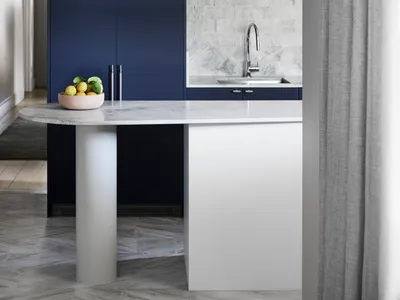 A modern kitchen with a marble countertop and navy blue cabinets.