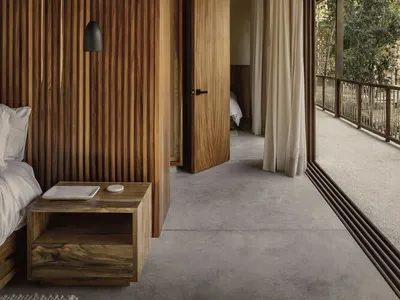 A minimalist bedroom with wooden walls and floors, featuring an open-plan design and natural light.