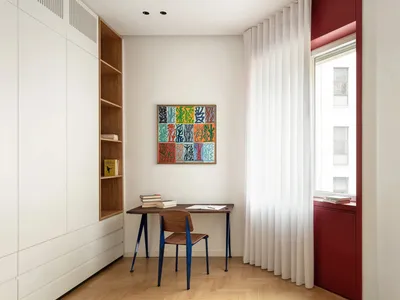 A minimalist home office featuring a wooden desk, chair, and white walls.