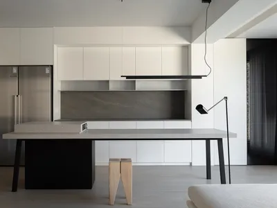 A minimalist kitchen featuring concrete finishes and white cabinetry.