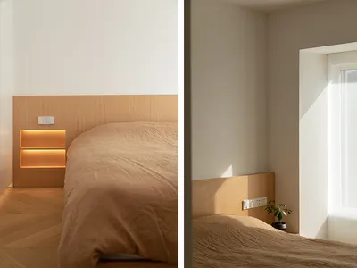 Modern, minimalist bedroom featuring wooden headboard and beige bedding.
