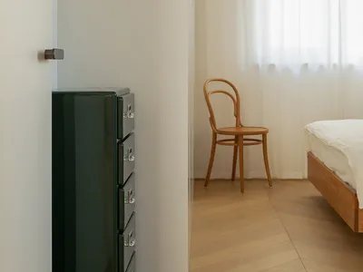 Minimalist bedroom with wooden furniture and a bed.