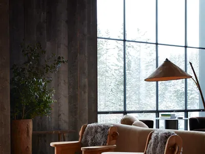 Industrial-style residential living room featuring wooden furniture and large windows with a snowy landscape view.