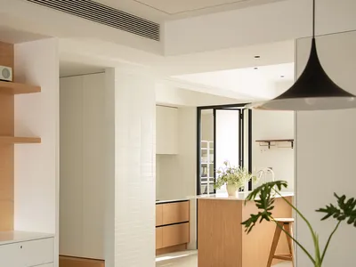 Modern minimalist residential kitchen featuring white cabinets and a wooden island.