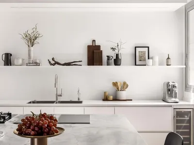 Modern minimalist kitchen featuring white marble countertops and white cabinets, with decorative items on shelves.