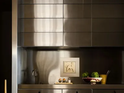 A modern minimalist kitchen with stainless steel cabinets and countertops, featuring a sleek and polished design.