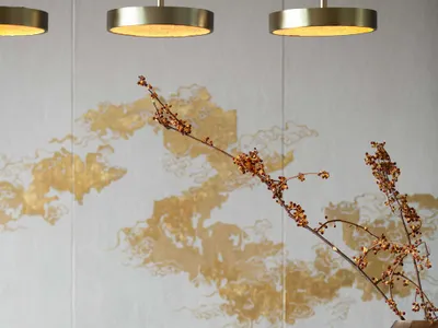 Modern restaurant dining area featuring metallic pendant lights and decorative branches in a vase.