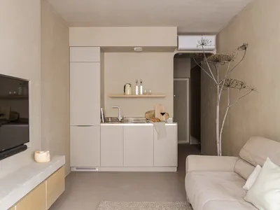A minimalist residential kitchen featuring concrete countertops, wooden cabinets, and metal accents.