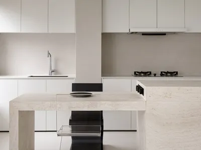 A minimalist kitchen with white marble countertops and a black and white marble table with a glass shelf.